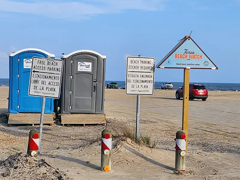 photo of the entrance signs and porta potties at bolivar flats beach texas